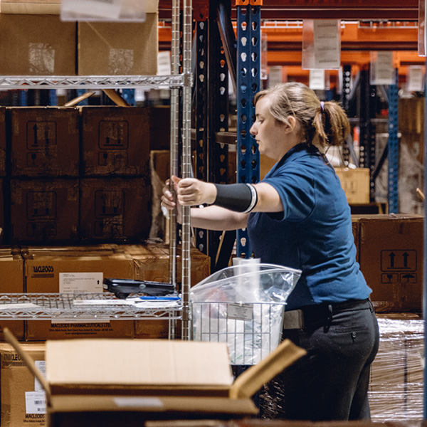 Female LSL Health Storage Worker Pushing a Cart inside Facility