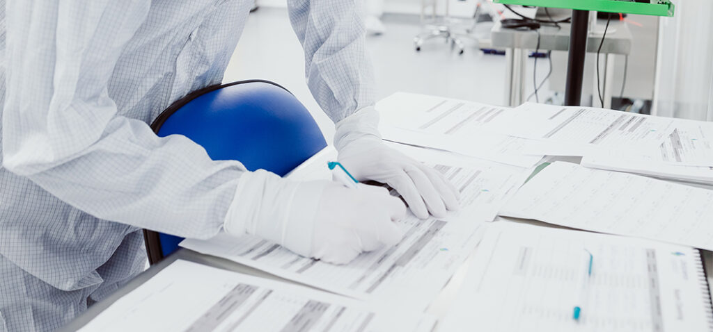 Worker in PPE Gear Signing Documents to Ensue Healthcare Compliance