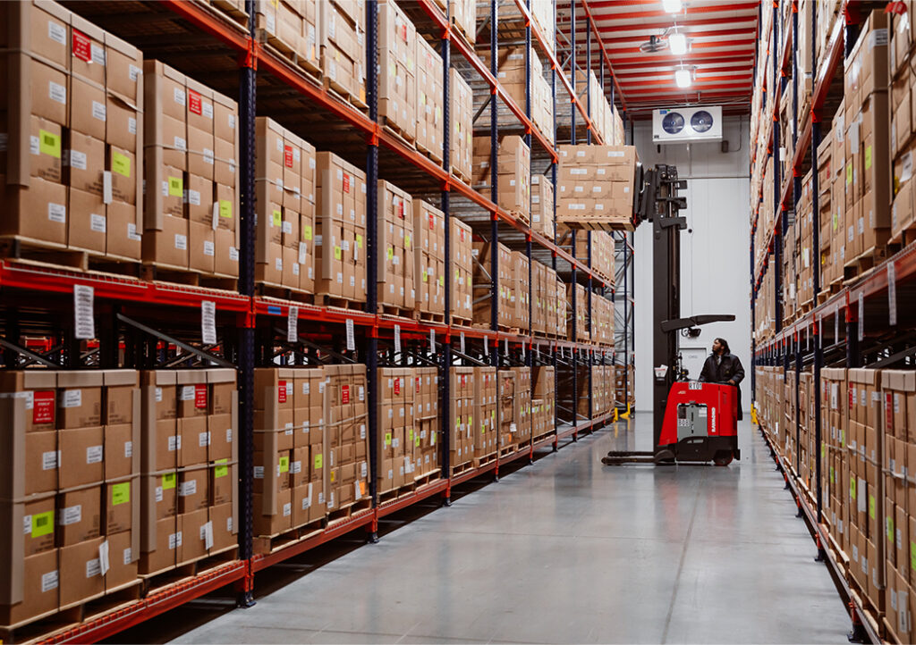 Worker with Forklift in LSL Warehouse Surrounded by Shelves of Boxes