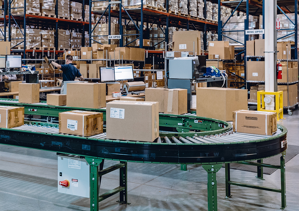 Conveyor with Boxes and Large Shelving Racks Filled with Healthcare Products inside LSL Warehouse