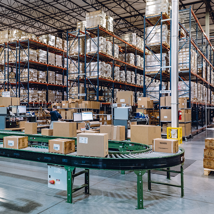 Warehouse Filled With Shelves of Boxes and a Conveyor Moving Boxes in Foreground