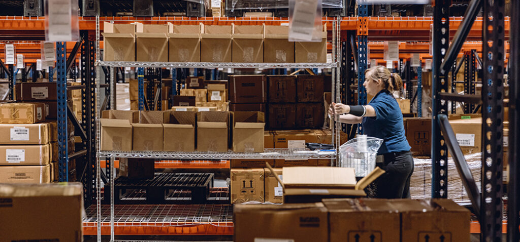 Woman Worker Pushing Picking Cart with Boxes in LSL Warehouse